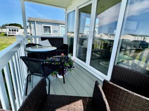 a porch with two chairs and a table on it at Craig Tara Holiday Park 101 Bay View in Ayr