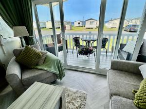 a living room with a couch and a table and a balcony at Craig Tara Holiday Park 101 Bay View in Ayr