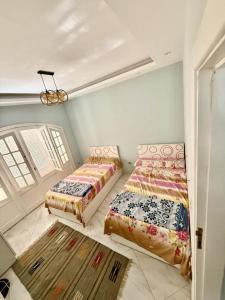 a bedroom with two beds and a chandelier at شاليه بقرية الفيروز in Qaryat Shurūq