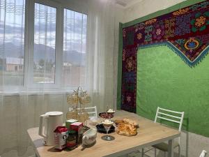 a dining room with a table and a green wall at Moto Guest House in Kochkorka +28 photos