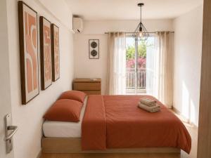 a bedroom with a bed with orange sheets and a window at Résidence Riviera Parc in Cagnes-sur-Mer