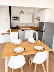 a kitchen with a wooden table and white chairs at Résidence Riviera Parc in Cagnes-sur-Mer +4 photos