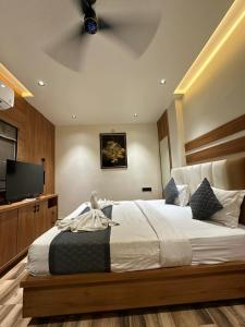 a bedroom with a large bed and a flat screen tv at Hotel the Infinity in Rajkot