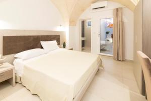 a white bedroom with a large bed and a bathroom at Vie Del Salento in San Pancrazio Salentino