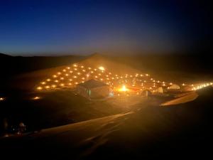 a group of tents with lights in a field at night at Caravane du bonheur in Mhamid