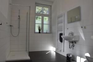 a white bathroom with a shower and a sink at Pension Alte Flugleitung in Stendal +61 photos