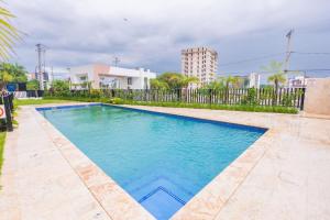 a swimming pool with blue water in front of a fence at Modern 3BR! 9fl, King Bed! Sti!, in Santiago de los Caballeros