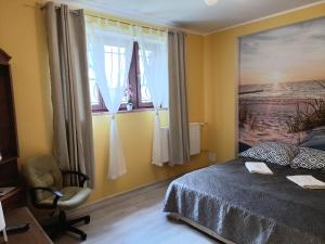 a bedroom with a bed and a chair and windows at Apartament Orłowo in Gdynia