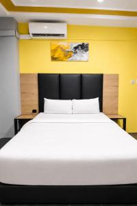 a bedroom with a large white bed with a yellow wall at Hotel Metro Lodge Xpress in Durban