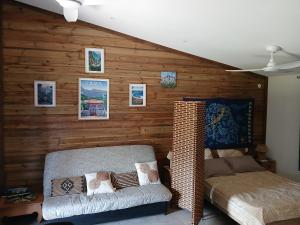 a bedroom with a wooden wall with a couch at La cabane au millieu du jardin in Saint-Louis
