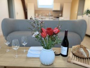 a table with a vase of flowers and a bottle of wine at Le Refuge des Clavendiers in Nuits-Saint-Georges +9 photos