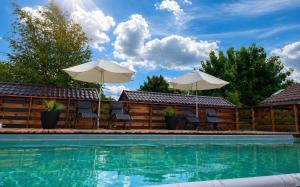 a swimming pool with chairs and umbrellas next to a house at Łeba Luxury House in Łeba +13 photos