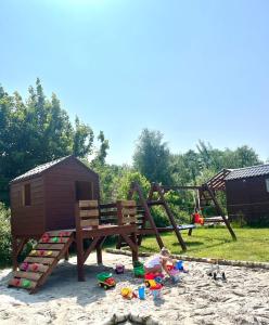 a playground with a swing and toys in the sand at Łeba Luxury House in Łeba