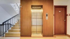a glass elevator in a building with a staircase at Hotel Holiday Park,Thalassery in Green Island +17 photos