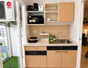 a small kitchen with a sink and a microwave at Modern 12th Floor Condo Walk to Phuket Old Town with Pool & Gym in Phuket