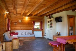 a living room with a white couch in a wooden room at Baita dei Fovi in Baselga di Pinè