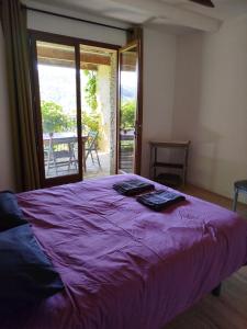 a bedroom with a purple bed and a door to a patio at La Bouriotte Gîtes in Labastide-Rouairoux