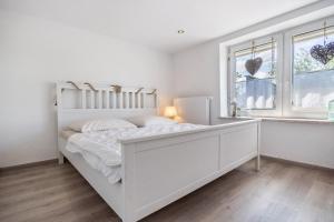 a white bedroom with a white bed and a window at Ankerhaus 2 in Trent