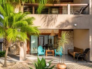 a house with palm trees and blue chairs at Residencial La Ferrugem - Garopaba/SC in Garopaba