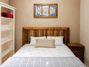 a bed with a wooden headboard and a stained glass window at Residencial La Ferrugem - Garopaba/SC in Garopaba