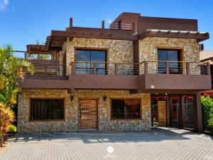 a stone house with a balcony on top of it at Residencial La Ferrugem - Garopaba/SC in Garopaba