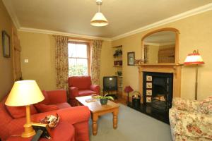 a living room with red furniture and a fireplace at Springburn Cottage in Strachur