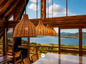 a dining room with a table and chairs and windows at Chalés da Lagoa - Imaruí/SC in Imaruí +52 photos