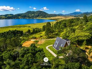 an aerial view of a house on a hill next to a lake at Chalés da Lagoa - Imaruí/SC in Imaruí