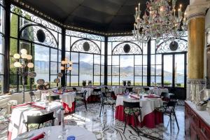 a dining room with tables and chairs and a chandelier at Villa e Palazzo Aminta - A Leading Hotel of The World in Stresa