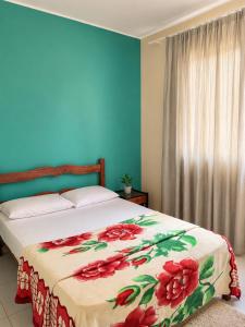 a bedroom with a bed with a red flower blanket at Cantinho Xodó in Capitólio