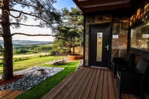 a house with a wooden deck with a door at Horizont Hillside Mályinka in Mályinka