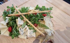 a plate of food with a salad on a wooden table at Hôtel restaurant ANGEL'S in Angles