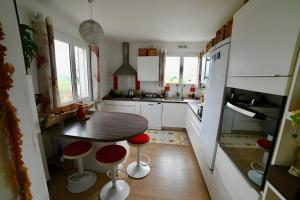 a kitchen with a wooden table and red chairs at Chambre d'hotes la Mainguy in Ruca