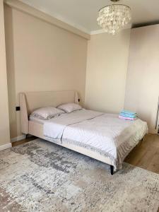 a bed in a bedroom with a chandelier at Lux Residence 2 in Osh