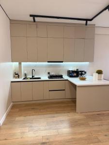a kitchen with white cabinets and a wooden floor at Lux Residence 2 in Osh