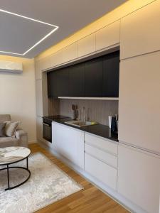 a kitchen with white cabinets and a couch and a table at Emma Luksuzni apartman Tuzla Musique in Tuzla