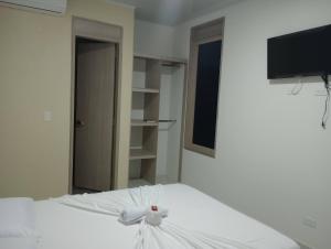 a bedroom with a white bed and a tv at hotel brb nature acacias in Acacías