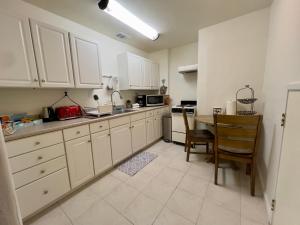 a kitchen with white cabinets and a table in it at Charming studio one mile from beach in Aptos