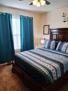 a bedroom with a bed with blue curtains and a ceiling fan at Xscapecation Oasis III in Tulsa