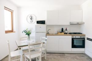 a kitchen with white cabinets and a table with chairs at Appartamento Sea - Tenuta Fascianello in Fasano