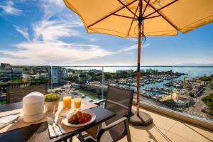 a table with a plate of food and an umbrella on a balcony at Hotel Mare in Lignano Sabbiadoro