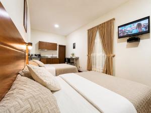 a hotel room with two beds and a flat screen tv at Suite Tarqui en el Centro Histórico in Cuenca
