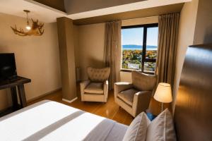 a hotel room with a bed and two chairs and a window at Esplendor by Wyndham El Calafate in El Calafate