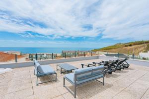 a group of benches on a patio overlooking the ocean at Eden Villa, with jacuzzi and ocean view in Casal do Cigano +40 photos