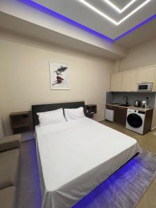 a bedroom with a white bed and a kitchen at Skampa Apartment in Elbasan