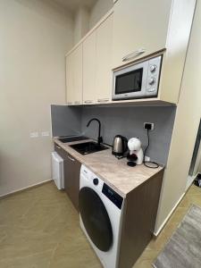 a kitchen with a microwave and a washing machine at Skampa Apartment in Elbasan