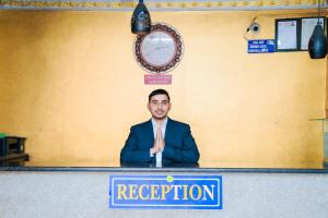 a man sitting at a podium in a room with a clock at Hotel Delite in Thapathali