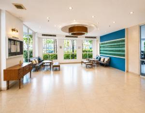 a large lobby with chairs and tables and windows at Modern 12th Floor Condo Walk to Phuket Old Town with Pool & Gym in Phuket