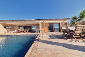 a house with a swimming pool and a table and chairs at Cala Di Mare Villa in Calvi
