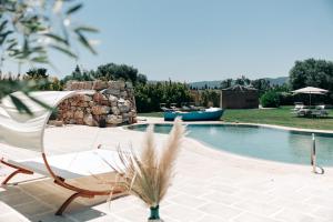 a pool with a chair and a boat in a yard at Appartamento Sea - Tenuta Fascianello in Fasano